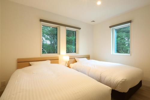 轻井泽Albatross Karuizawa的卧室设有两张床,带两个窗户