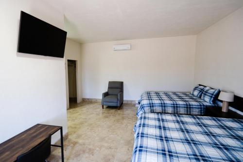 San QuintínHOTEL & RV PARK ROSA EVELYN的客房设有两张床、一台电视和一把椅子。