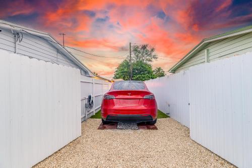 迈阿密花园Smart Tiny House Garden的两座白色围栏之间停着的一辆红色汽车