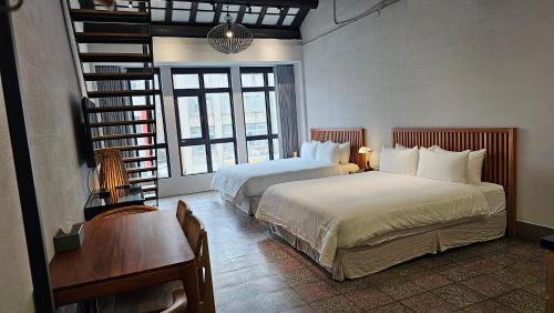 台南璿旅店的一间卧室配有两张床、一张桌子和一张书桌