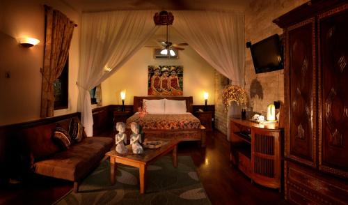 瑟古邦坦帕瑟南Spa餐饮度假酒店的一间卧室配有一张床、一张沙发和一张桌子