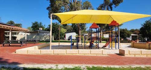 珀斯班可斯艾旅游公园酒店的公园里一个带黄色遮阳伞的游乐场