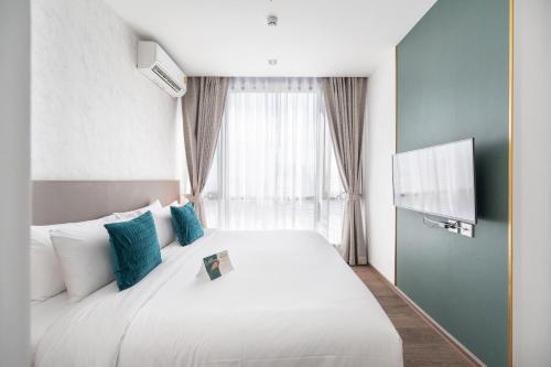 曼谷The Rich Residence Sukhumvit Nana的卧室配有带蓝色枕头的大型白色床