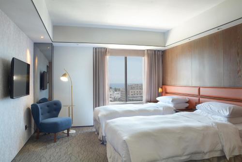 台东台东桂田喜来登酒店的酒店客房,设有两张床和一张蓝色椅子