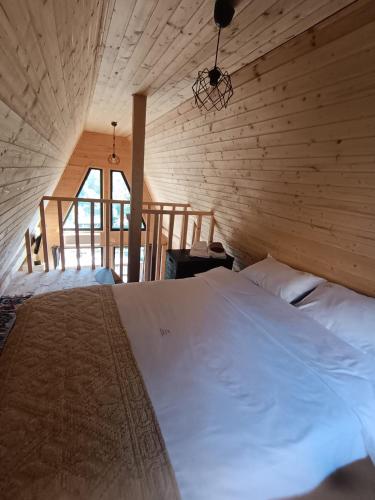 RuncuCarpatinA Rustic House的卧室配有一张白色大床,位于木墙内
