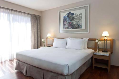 科尔多瓦科尔多瓦乌尔巴诺NH酒店的卧室设有一张白色大床和一扇窗户。