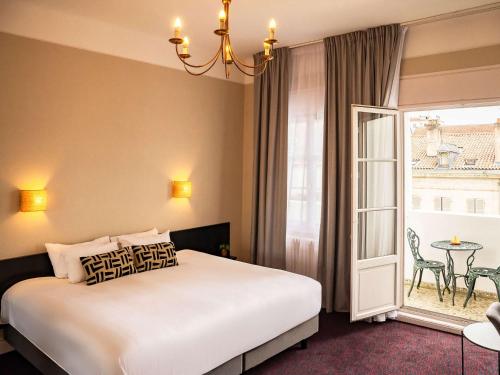 巴约讷巴约讷中心格兰德美居酒店的一间卧室配有一张床、一张桌子和一个窗户。