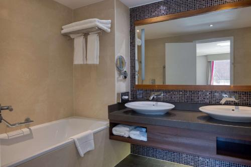 剑桥剑桥市中心希尔顿酒店的浴室设有2个水槽、浴缸和镜子