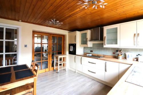 贝尔法斯特St James's Rd的厨房配有白色橱柜和木制天花板