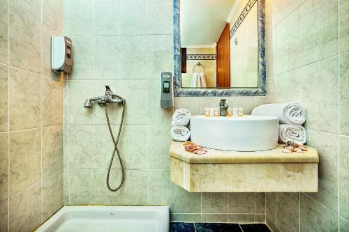 卡尼奥提Elinotel Polis Hotel的浴室配有盥洗盆、镜子和浴缸