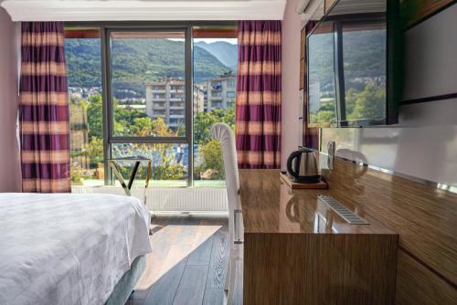 伯萨TOK EPİK HOTEL的酒店客房设有一张床、一张书桌和窗户。