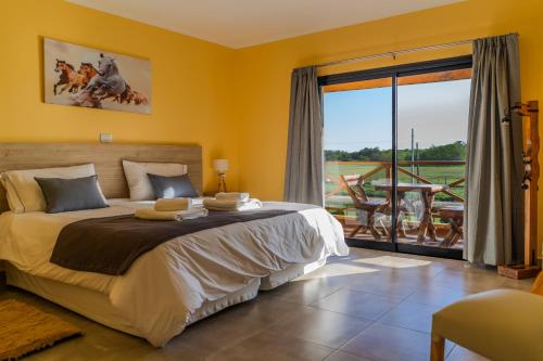 圣安东尼奥德阿雷科Un Alto en la Huella - Hotel Spa & Wellness Resort的一间带大床的卧室和一个阳台