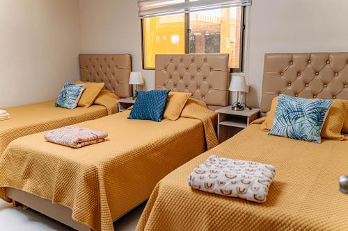 皮卡2 Cabañas para 5 Personas Oasis Pica-Matilla的客房设有3张带黄色床单和蓝色枕头的床。