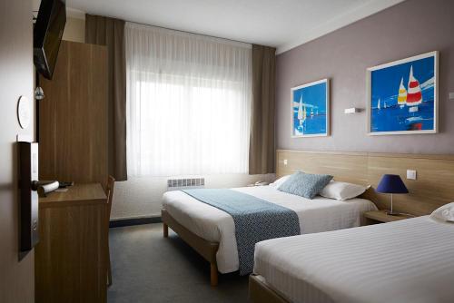 洛里昂The Originals City, Hôtel Les Océanes, Lorient的酒店客房设有两张床和窗户。