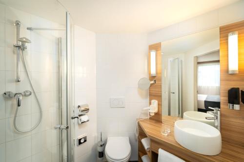 维也纳Leonardo Hotel Vienna Schönbrunn的浴室配有卫生间、盥洗盆和淋浴。