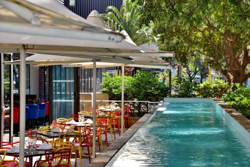 开普敦Fountains Hotel的餐厅旁的游泳池配有桌椅