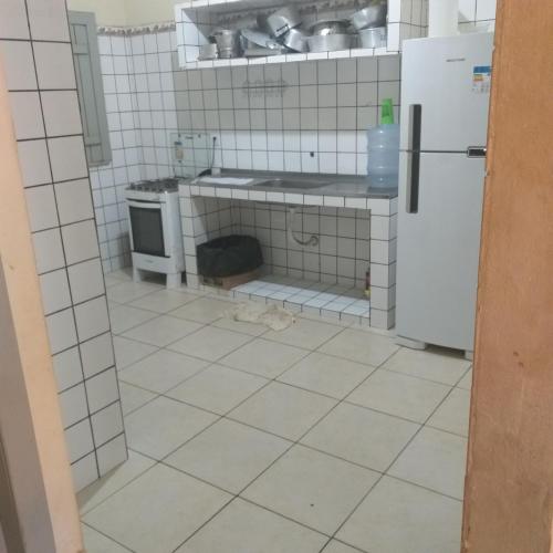 伊列乌斯Casa de Praia的厨房铺有白色瓷砖地板,配有冰箱。