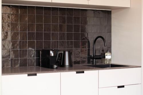 斯海弗宁恩By Friso Den Haag的厨房的墙壁上铺有黑色瓷砖,设有水槽