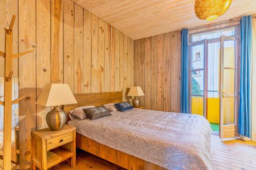 阿卡雄La Maison des Huîtres的一间卧室设有一张床和木墙