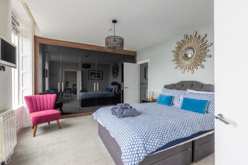 莱瑟姆-圣安妮BEACH VIEW - Amazing Sea Views的一间卧室配有一张床和一张粉红色的椅子