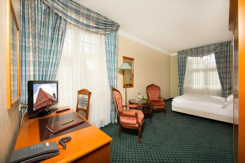 格赖夫斯瓦尔德科隆普林兹酒店的酒店客房设有一间带一张床和一张书桌的卧室