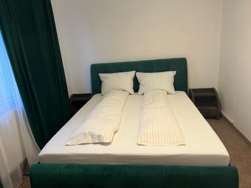巴克乌Green Apartament的一张带绿色床头板的床和两个枕头