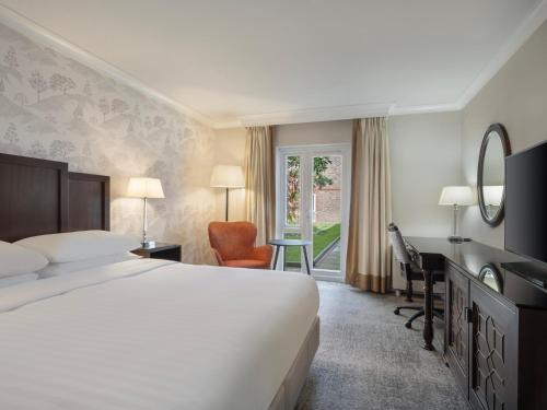 梅德斯通Delta Hotels by Marriott Tudor Park Country Club的配有一张床、一张书桌和一扇窗户的酒店客房