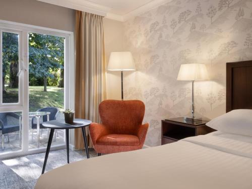 梅德斯通Delta Hotels by Marriott Tudor Park Country Club的酒店的客房 - 带一张床、椅子和窗户