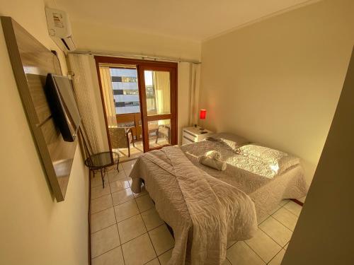 卡庞达卡诺阿Apartamento de frente com sacada no centro de Capão da Canoa的一间卧室设有一张床、一个窗口和一台电视