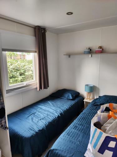 瓦尔拉普拉日camping sable du midi 4 etoile的一间卧室设有两张床和窗户。