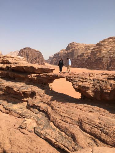 亚喀巴Bedouin experiences的两个人在沙漠的一座石桥上行走