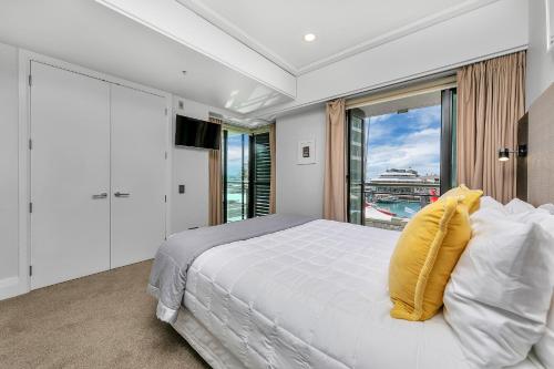 奥克兰Fabulous Corner Apartment w/ Dazzling Harbour View的卧室设有白色的床和大窗户