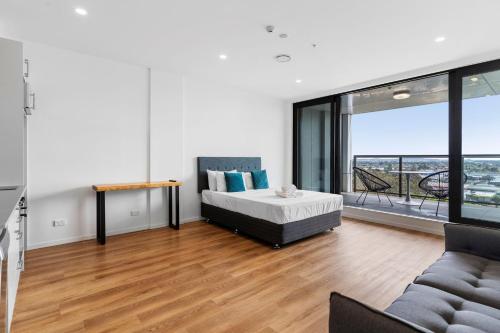 奥克兰Manukau Studio Apartments的一间卧室配有一张床、一张沙发和一个大窗户