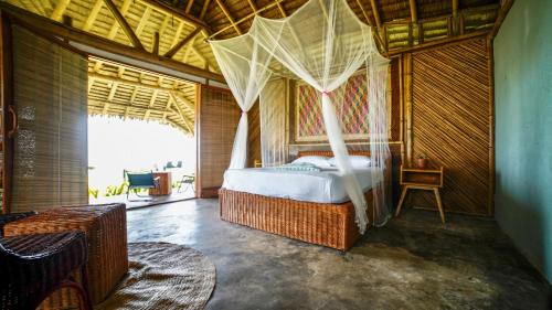 爱妮岛Eco Sanctuaries Nature Lodge Nacpan Beach, El Nido的一间卧室配有一张带蚊帐的床