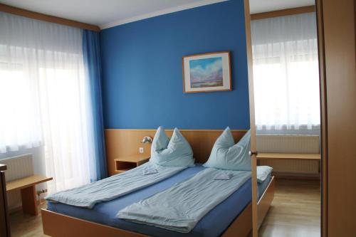 滨湖波德斯多夫Gästehaus Lokalaugenschein的一间卧室设有蓝色的墙壁和一张带枕头的床。