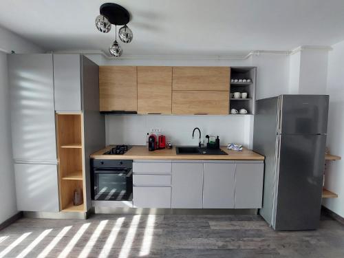普洛耶什蒂Raluca cozy apartment's的厨房配有白色橱柜和不锈钢冰箱