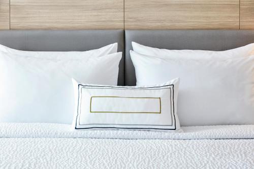 卡梅尔印第安纳波利斯卡梅尔春季山丘套房酒店的床上的白色枕头和白色枕头