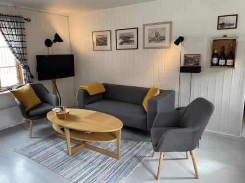 斯塔姆松Charming Rorbu Stamsund Lofoten的客厅配有沙发、两把椅子和一张桌子