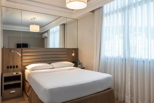 弗洛里亚诺波利斯蓝树高级弗洛里亚诺波利斯旅馆的一间卧室设有一张大床和一个大镜子
