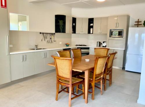 伊登Central Beach house on Chandos的厨房配有木桌、椅子和冰箱。