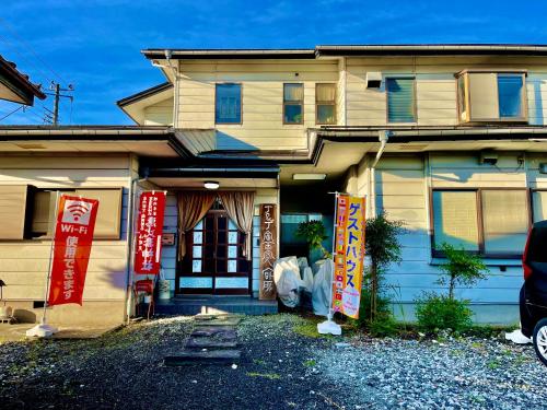 富士吉田市T&T Fujiyama Guest House的前面有标志的房子