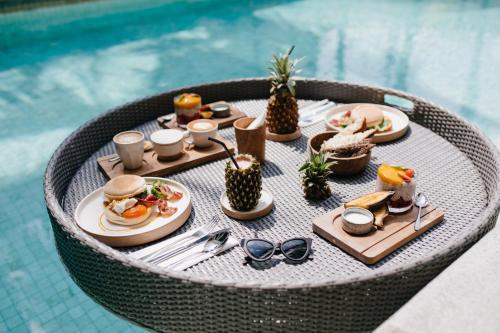 阿克拉Lukas Garden Accra的一张桌子,桌子上摆着食物和饮料,在游泳池边