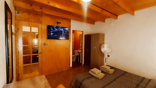 圣佩德罗·德·阿塔卡马Hostal Yurak的卧室配有一张床,墙上配有电视