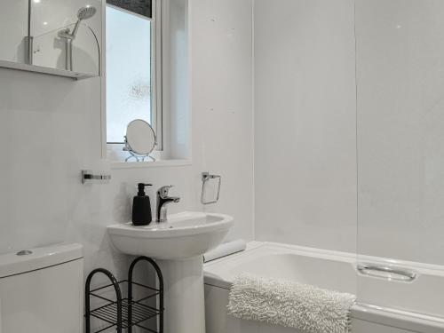 波特帕特里克Anchor Cottage的白色的浴室设有水槽和浴缸。