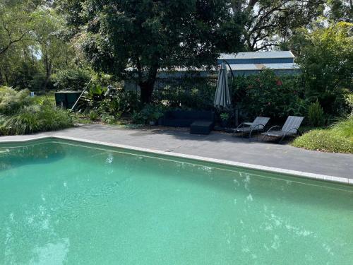 贝利Haven Villa的一个带两把椅子和遮阳伞的游泳池