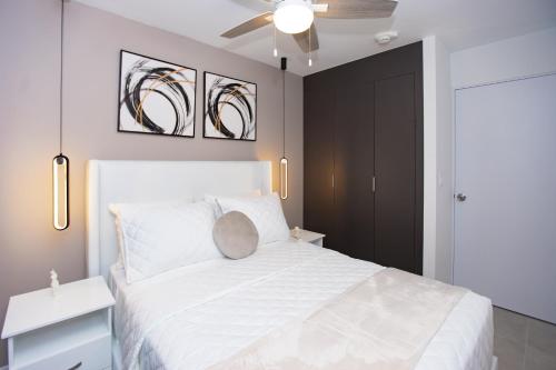 圣何塞Exclusivo apartamento piso 23, Sky Garden的卧室配有白色的床和吊扇