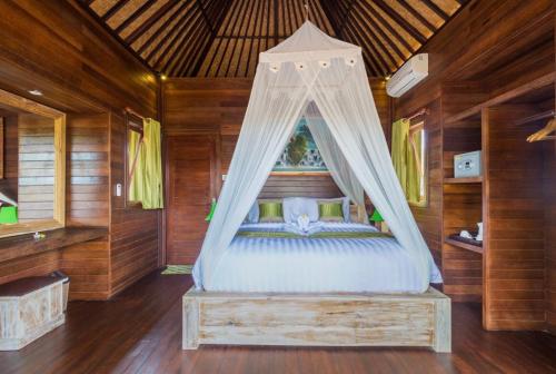 蓝梦岛Taman Sari Villa, Nusa Lembongan的木制客房内的一间卧室配有一张天蓬床
