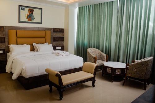 迪马普尔Hotel Grand Lotus的一间卧室配有一张床、两把椅子和一张桌子