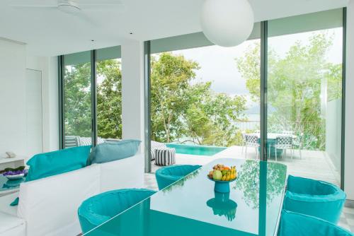 班巴克洛COMO Point Yamu, Phuket- SHA Extra Plus的客厅配有玻璃桌和蓝色椅子