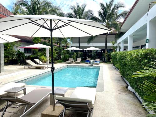 拉威海滩Lotus Bleu Resort & Restaurant的一座带椅子和遮阳伞的游泳池位于大楼旁